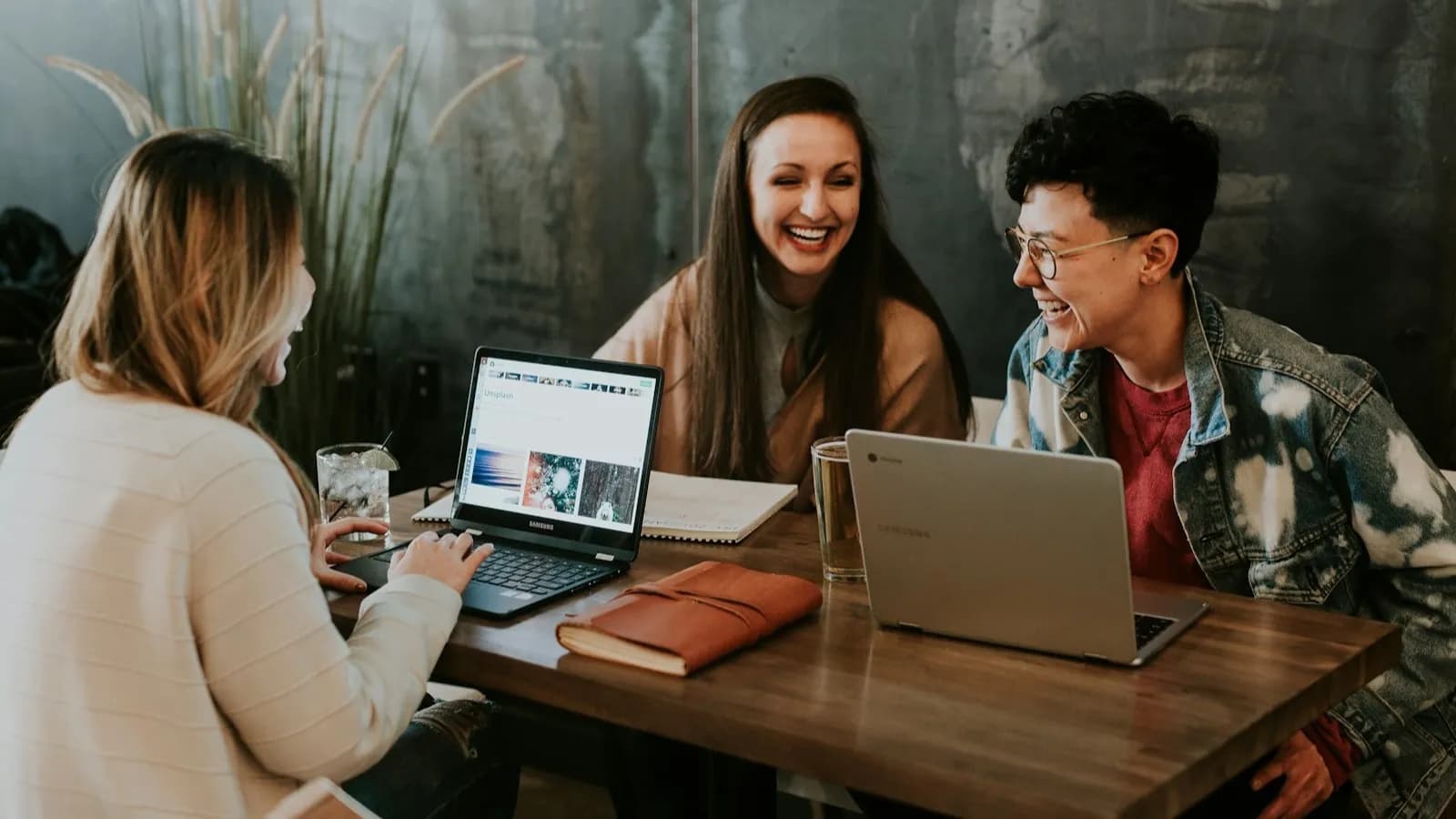 Three LSJHML students collaborating with laptops at a London cafe table